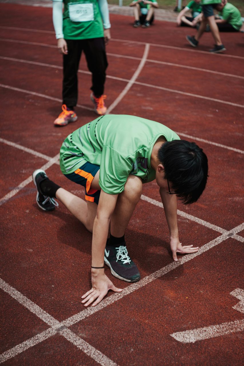 Young athlete in a sprint-start crouch on the track